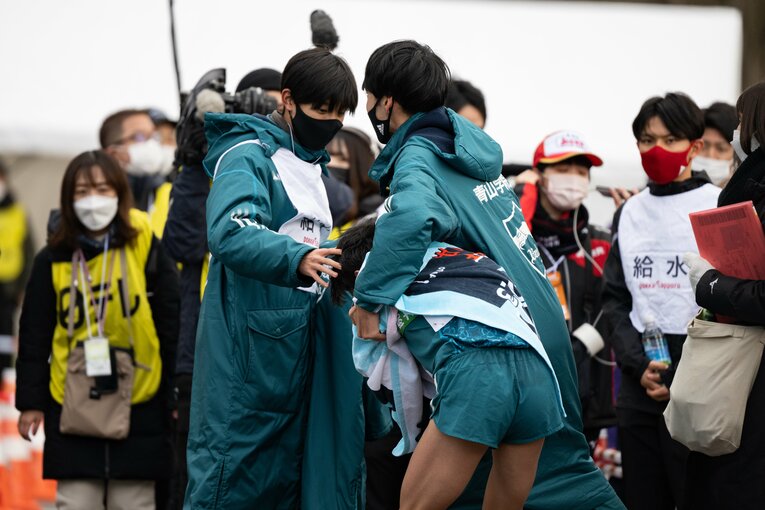 5区で首位・駒澤大と差を離された脇田はうずくまって、仲間に支えられる　©Nanae Suzuki