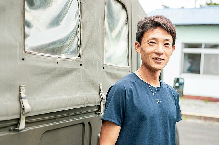 陸上部の練習でも使うジープの前で、穏やかな笑みを浮かべる宮原徹。自衛隊最強ランナーだ。 ／ photograph by Kiichi Matsumoto