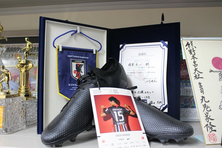 JFAから福重良一監督に贈られた感謝状と、鎌田大地のスパイク　©Number Web