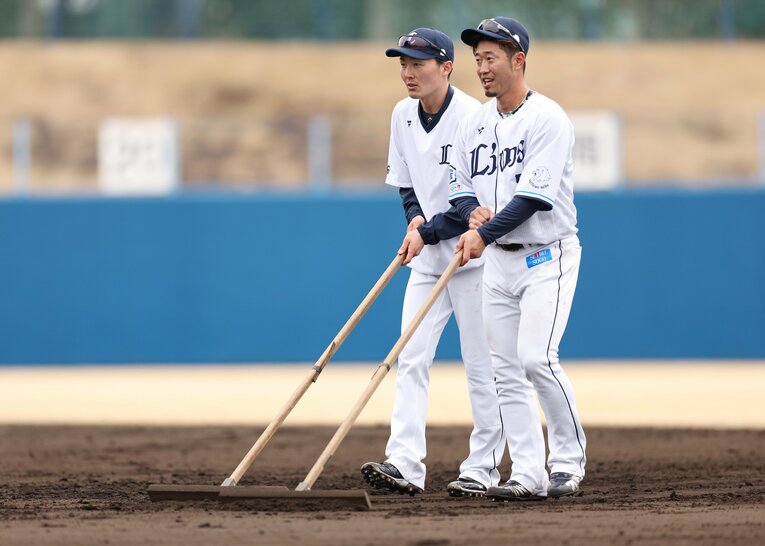 守備練習後にグラウンドをならす源田と外崎（23年2月）©︎JIJI PRESS
