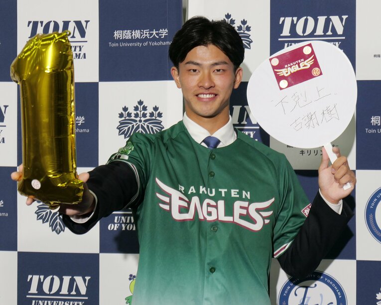 楽天に1位指名され、笑顔でポーズを取る古謝樹（桐蔭横浜大）　©JIJI PRESS