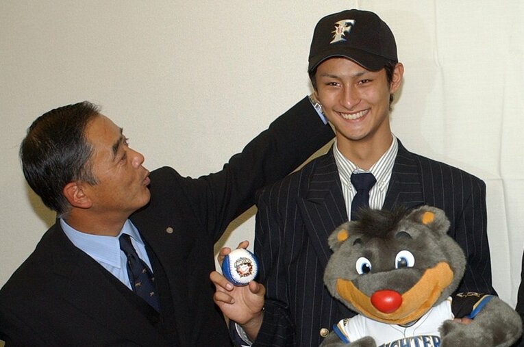 2004年12月、日本ハムとの仮契約の記者会見後、笑顔を見せる宮城・東北高校のダルビッシュ有投手と今成泰章担当スカウト ／ photograph by JIJI PRESS