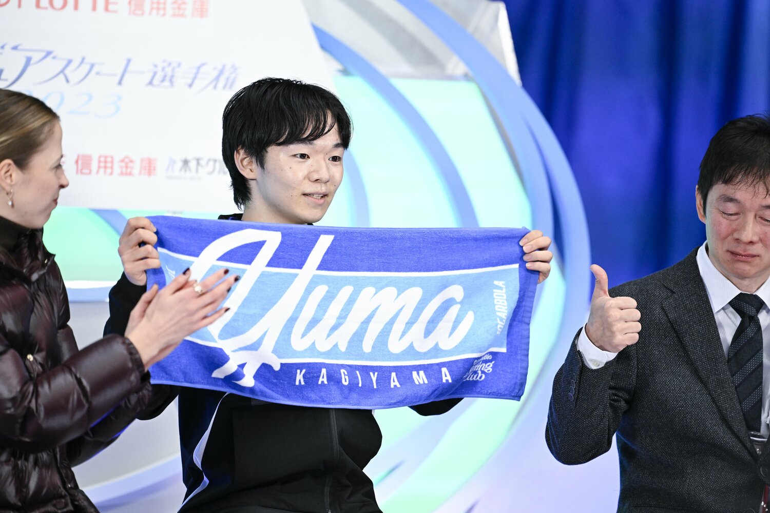フリーは198.16点の首位。Yumaのタオルを掲げる鍵山優真。コストナーコーチは拍手、鍵山正和コーチは親指を立ててナイスのリアクション　©︎Asami Enomoto