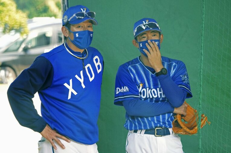 嘉手納キャンプのブルペンで三浦大輔監督と話し込む、仁志敏久二軍監督（右）。背番号87は巨人時代の8と横浜時代の7を組み合わせたもの ／ photograph by KYODO