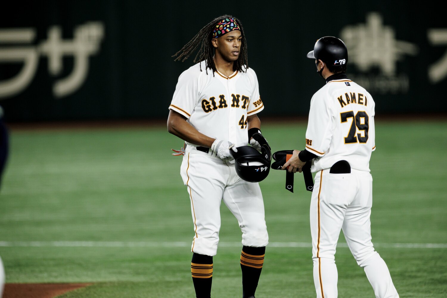 塁上で外野守備と走塁を兼任する亀井コーチと話すウォーカー　©Kiichi Matsumoto