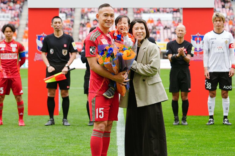 J1通算100試合出場を記念したセレモニーでは妻・真優さんと息子の瑛翔くんも登場。家族3人で写真におさまった（2026年4月）　©ALBIREX NIIGATA