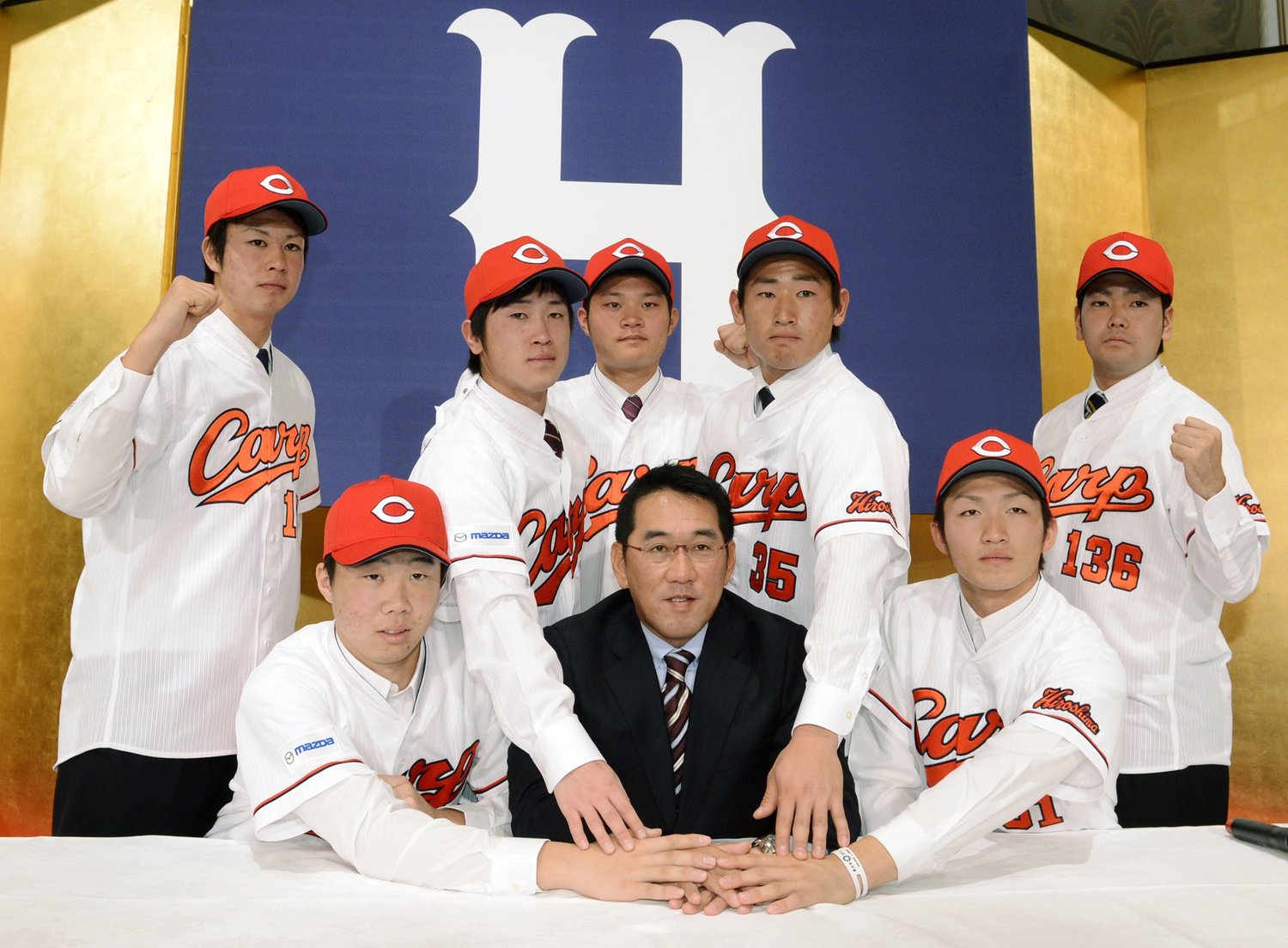 2012年、広島の新入団記者会見でポーズを取る（前列左から反時計回りに）高橋大樹外野手、野村監督、鈴木誠也内野手、森下宗外野手、下水流昂外野手、美間優槻内野手、上本崇司内野手、辻空投手　©共同通信社