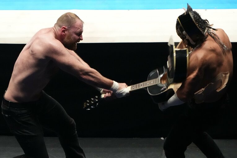 エル・デスペラードの脳天にギターを振り下ろすジョン・モクスリー（クリックすると「この記事の写真」に飛びます。流血等の過激な写真を含みますのでご注意ください）