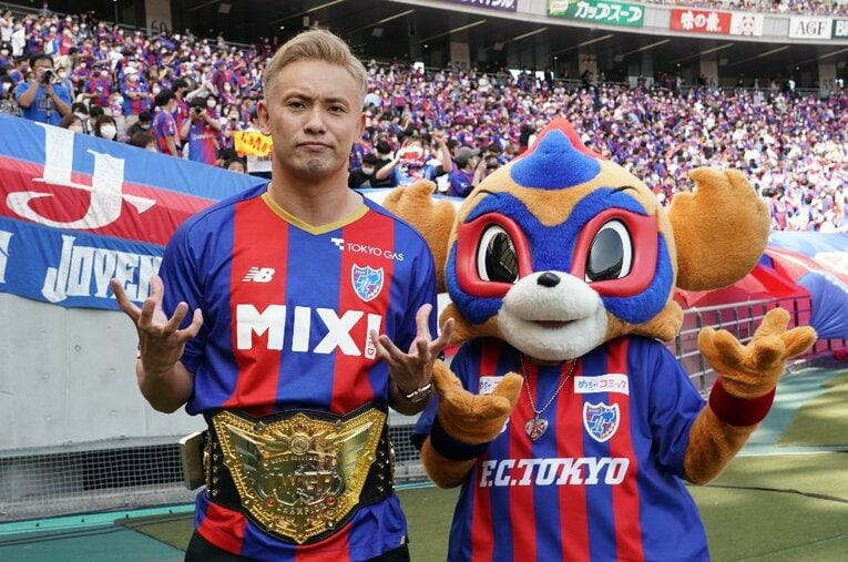 FC東京のユニフォームを着たオカダ・カズチカと、マスコットの東京ドロンパ。4月10日の味の素スタジアムには2万人を超える観客が詰めかけた ／ photograph by Essei Hara