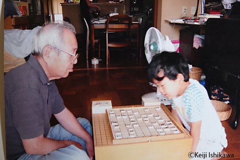 幼い頃の藤井聡太竜王が祖父と将棋をする姿　※写真を複写　©Keiji Ishikawa