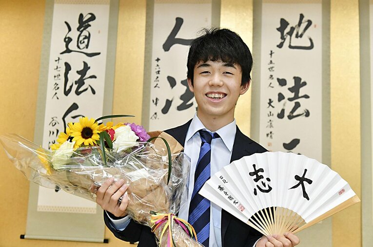 2017年の藤井聡太四段（当時）。花束と「大志」と記した扇子を手に笑顔 ／ photograph by Kyodo News