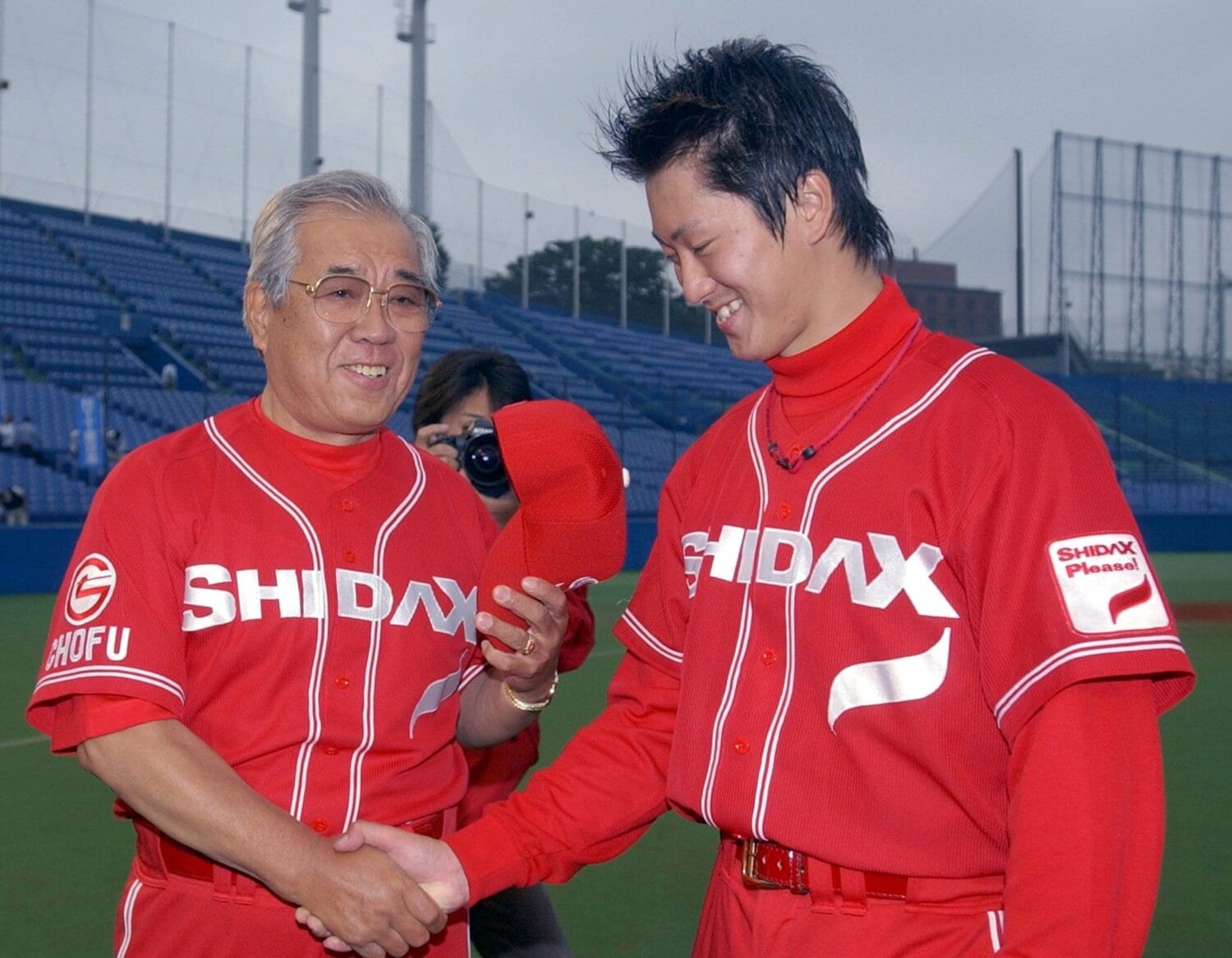 野間口貴彦(右)と握手する野村克也監督。2003年、都市対抗野球出場を決めて。野間口は翌年ドラフトでジャイアンツへ ©Sankei Shimbun