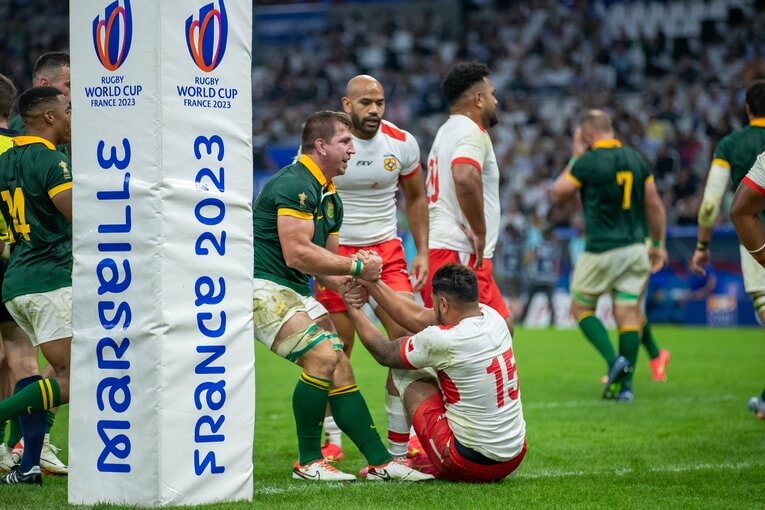 トンガ戦の終盤、トライを決めたクワッガ・スミス。すぐさま、今季からブルーレヴズでチームメイトになるチャールズ・ピウタウ（右）を引き上げた　©︎Yuuri Tanimoto