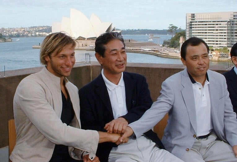 2003年12月、阪神のV旅行（オーストラリア）で。ペラハウスをバックに、競泳界のスーパースター、イアン・ソープと握手する星野、岡田彰布　©JIJI PRESS