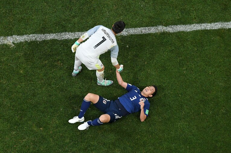 グラウンドに寝転ぶ昌子に手を差し伸べるGK川島　©︎Getty Images