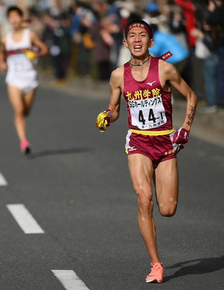 男子1区終盤で先頭に立ち、たすきを手に中継所に向かう九州学院（熊本）の鶴川正也　©JIJI PRESS