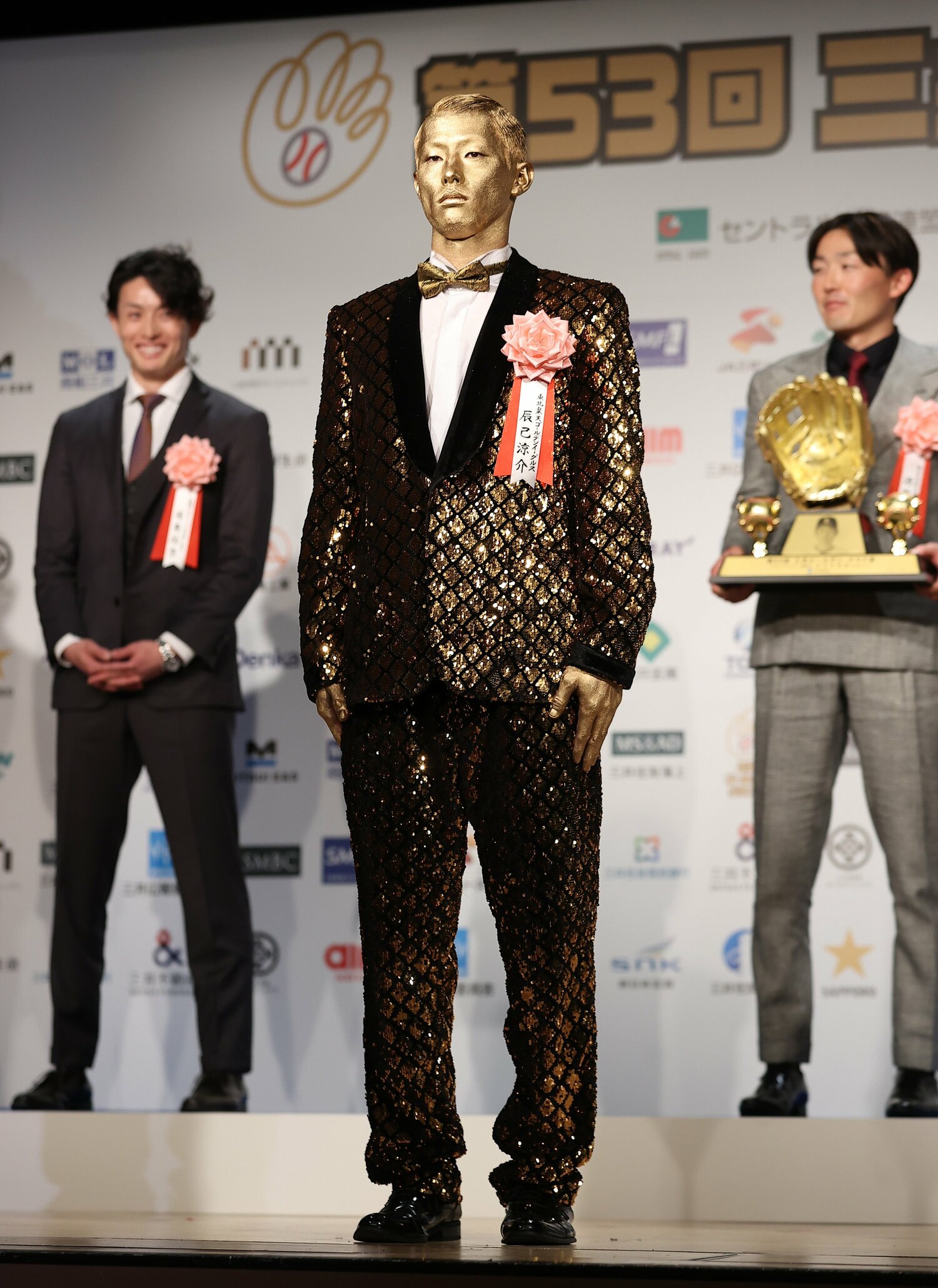 これが衝撃の「全身金ピカ」姿。共に壇上に並んだ選手たちも笑いを堪えきれない　©︎SANKEI SHIMBUN