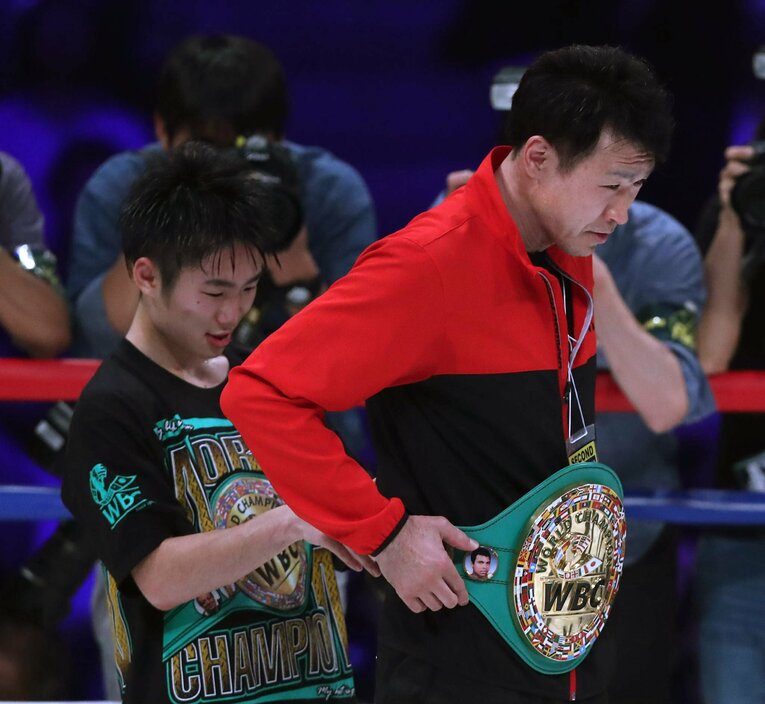 父にベルトを巻いてあげる拳四朗25歳　©JIJI PRESS