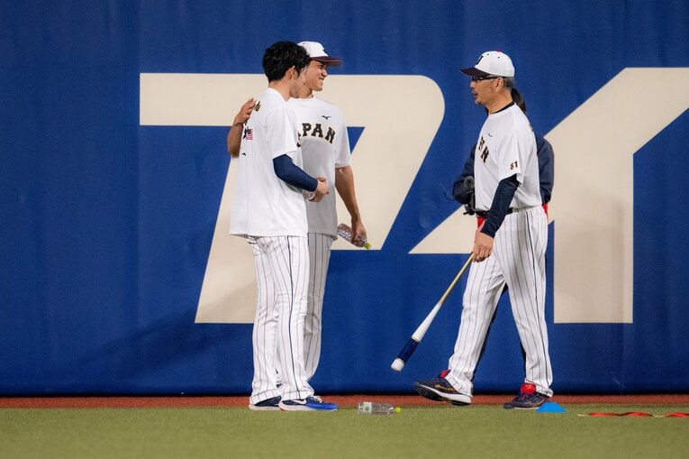 佐々木朗希の肩に手を添えながら吉井コーチと話す大谷　©︎Nanae Suzuki