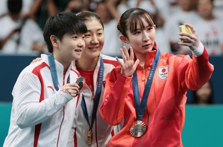 卓球女子シングルスのメダルセレモニー。中国の陳夢（中央／金メダル）、孫穎莎（左／銀メダル）とセルフィーを撮影する早田ひな ／ photograph by Getty Images