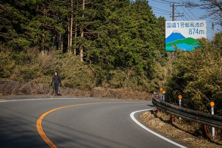 強風が吹きつけるなか、国道1号最高地点付近を歩く筆者　©Shiro Miyake