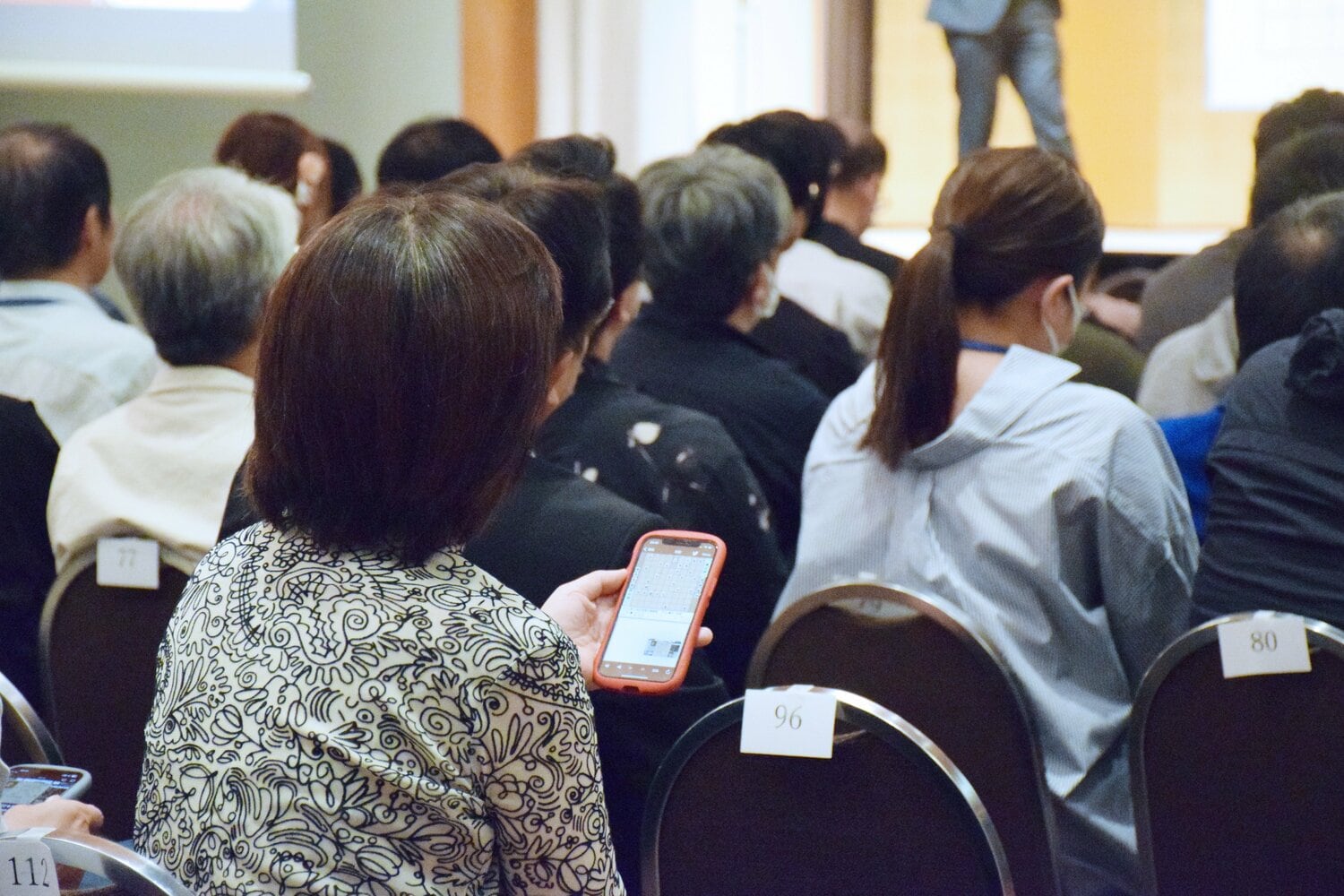 大盤解説会でスマホを確認する人々　©JIJI PRESS