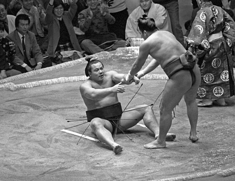 背中をつけた千代の富士（左）を起こす寺尾（平成元年初場所／1989年1月16日）　©︎KYODO