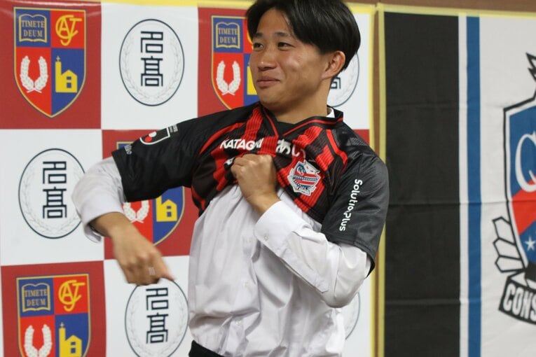 照れくさそうに制服の上からユニフォームを着る名古屋高校FW原康介（3年）©︎Takahito Ando