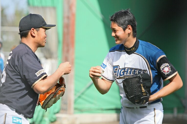 楽しげにグータッチをする大嶋匠さんとルーキー時代の大谷翔平　©JIJI PRESS
