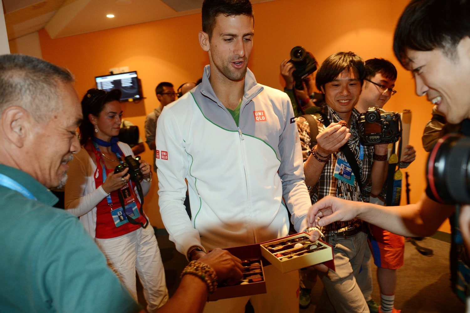 会見に集まった記者やカメラマンにチョコレートを配るジョコビッチ ©Getty Images