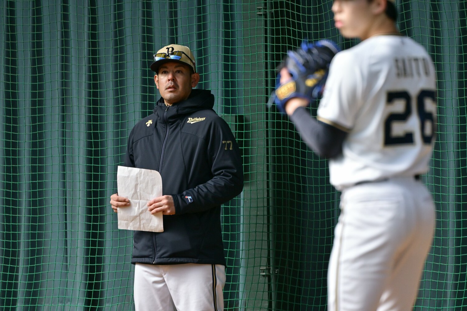 春のキャンプで若手投手のブルペン投球を見守る比嘉コーチ　©︎Hideki Sugiyama