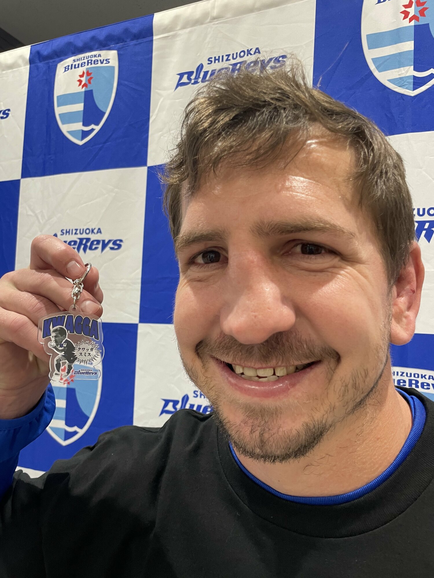 自身のキーホルダーを手に、笑顔のクワッガ・スミス。曲がった鼻は「ラグビーの勲章」ではなかった……　©︎SHIZUOKA BlueRevs