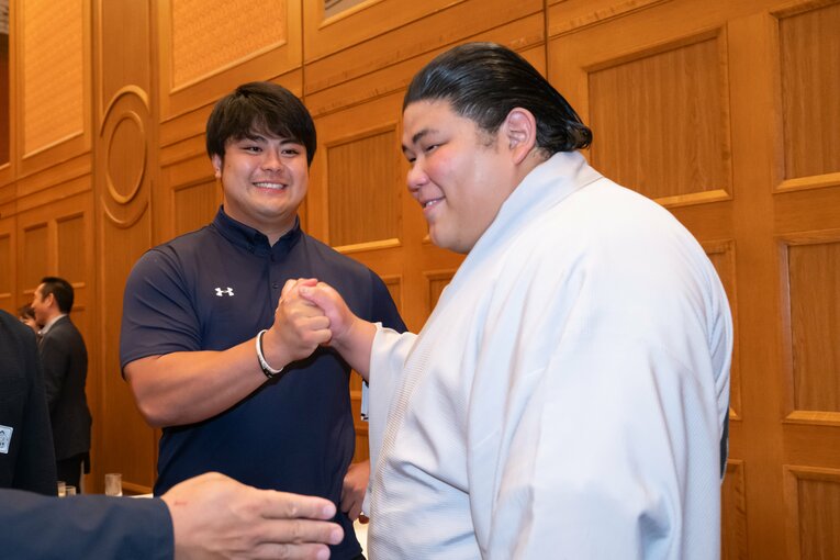 名古屋場所の千秋楽打上げパーティ。伯桜鵬（手前）と元アマ横綱・花田秀虎が握手を交わす　©Miki Fukano