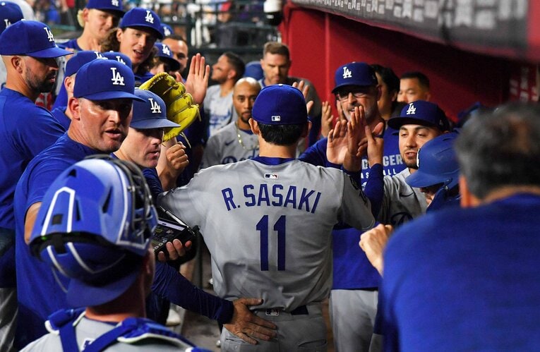 初リリーフを成功させベンチで笑顔の選手たちに迎えられる佐々木　©JIJI PRESS