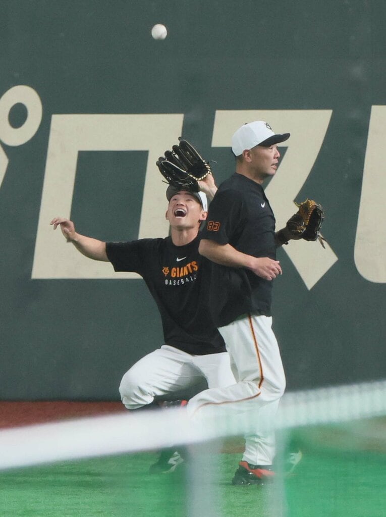 試合前練習のノック。阿部監督（右）が目の前を“わざと”通り過ぎ、驚きながら捕球する萩尾匡也　©Sankei Shimbun