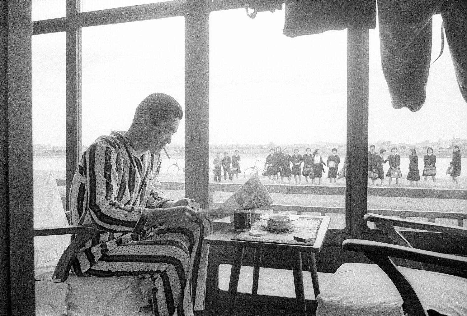 宮崎キャンプ、くわえタバコで新聞を読む長嶋茂雄（1960年撮影、当時23歳）。外には女学生たちの姿　©BUNGEISHUNJU