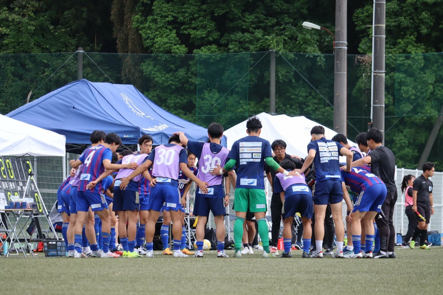 今年から日比は順天堂大学サッカー部で監督を務める（写真、円陣奥）