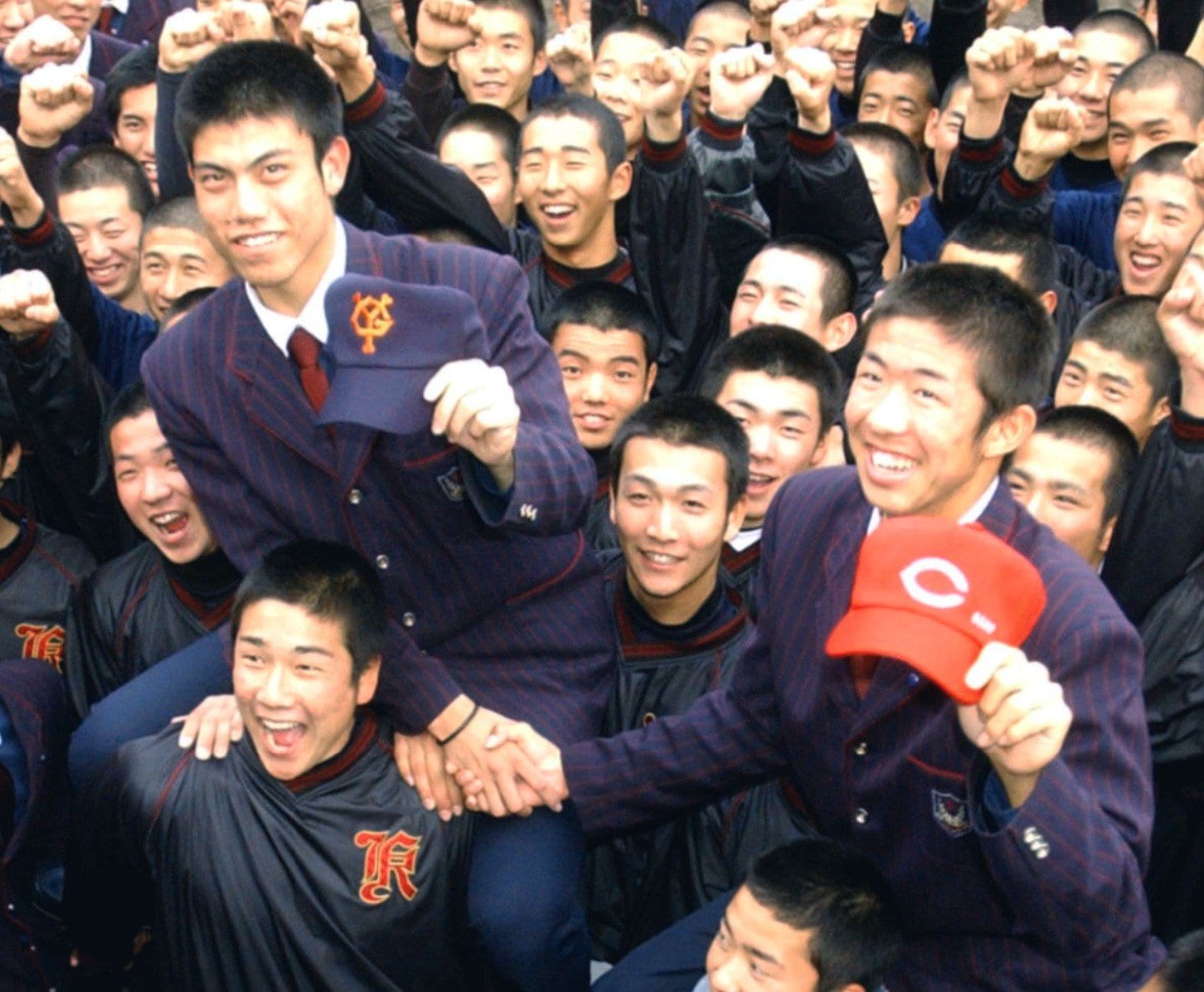 2003年のドラフト、巨人から2位指名された西村健太朗投手(左)と広島から1位指名された白浜裕太捕手。広陵高のチームメートから祝福を受ける ©KYODO