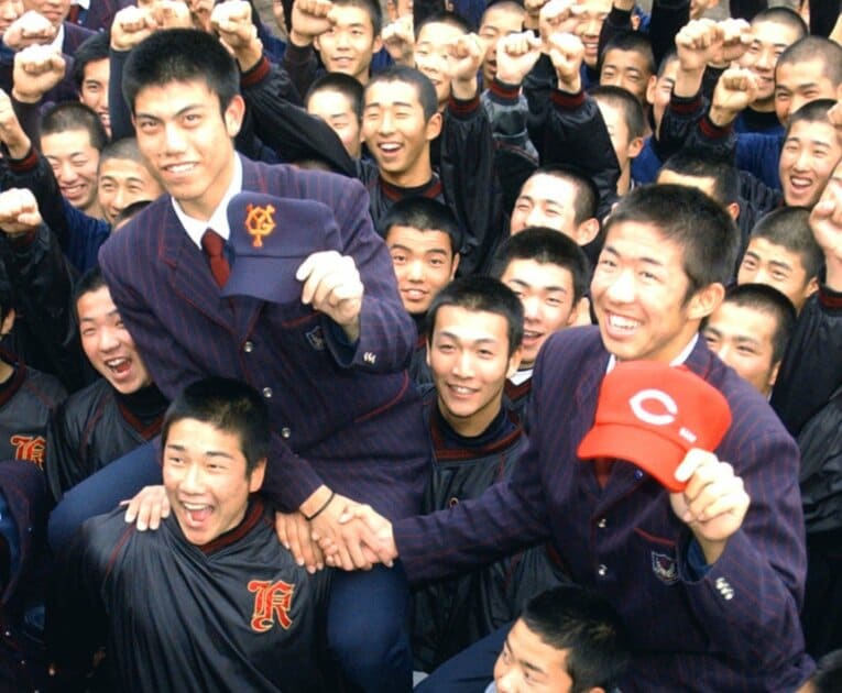 2003年のドラフト、巨人から2位指名された西村健太朗投手（左）と広島から1位指名された白浜裕太捕手。広陵高のチームメートから祝福を受ける　©KYODO