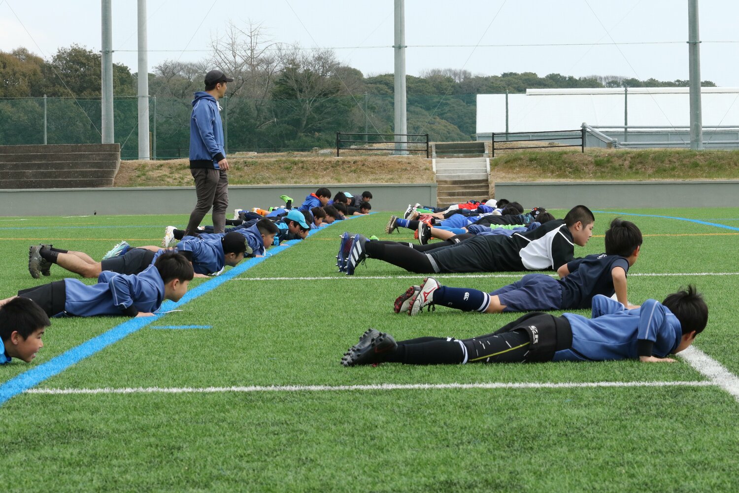 小中学生たちと一緒にトレーニングに励む信也さん。左はアカデミーの君島良夫代表　写真提供：Elite Rugby Academy