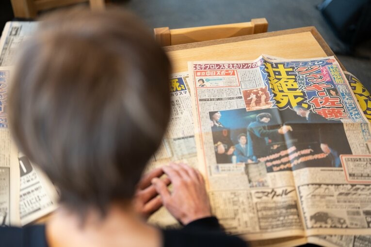ジャッキー佐藤の死去を報じる当時の新聞を読むマキ上田　©Shiro Miyake