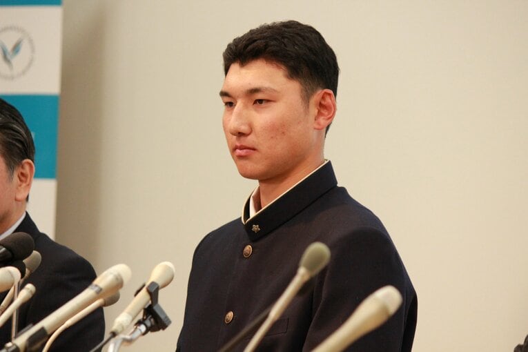 日本ハムから指名を受け、表情を変えないように努める菰田（中央）　©Yusuke Kondo