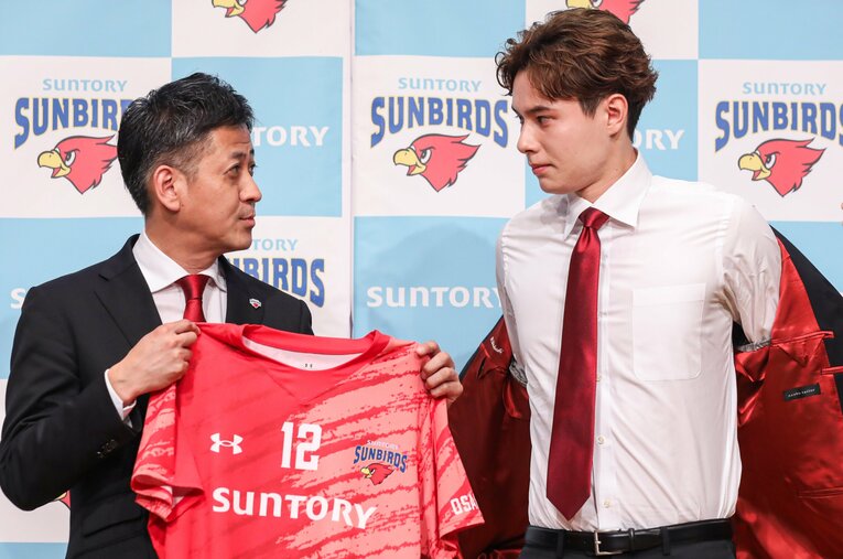 サントリーサンバーズの新ユニフォームを栗原圭介GMから受け取る高橋藍（22歳）。背番号は日本代表でもお馴染みの「12番」を譲り受けた ／ photograph by SUNTORY SUNBIRDS