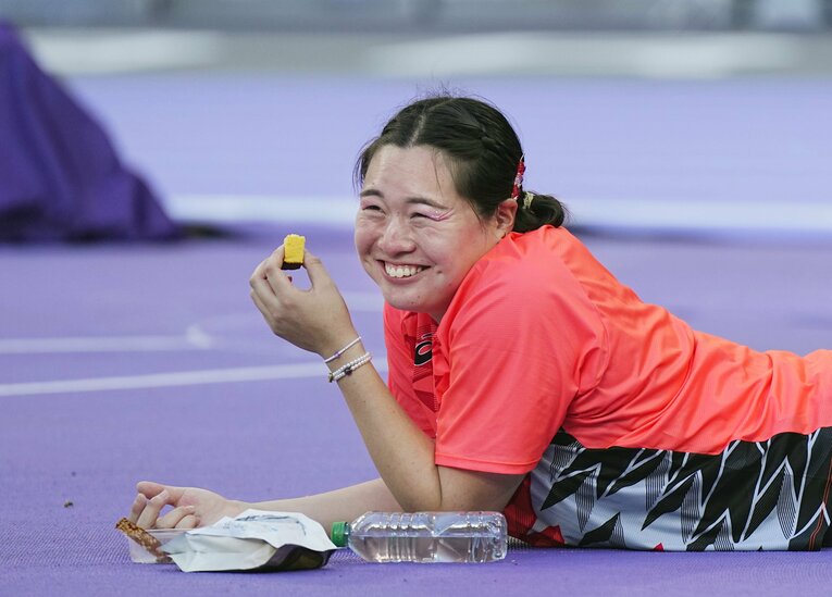 試合中、うつ伏せに寝そべりながらカステラを食べる北口榛花　代表撮影