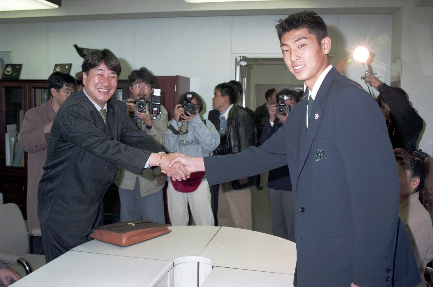 1995年11月、仮契約を前に、当時ダイエーの永山スカウト（左）と握手を交わす斉藤和巳 　©KYODO