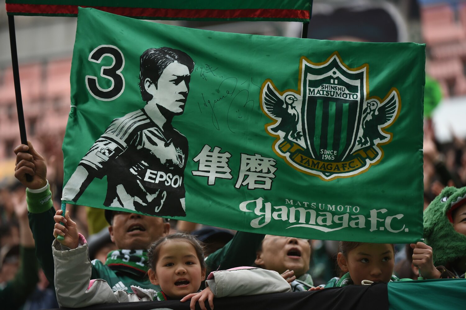 「３ 隼磨」のフラッグを掲げる松本山雅のサポーター　©︎Getty Images