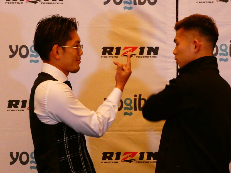 ニヤつきながら中指を突き立てる皇治と、その様子を見つめるYA-MAN　©Koji Fuse