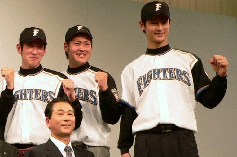 新入団選手発表の場で記念撮影する新人のダルビッシュ有（右端）と高田繫GM（手前）　©JIJI PRESS
