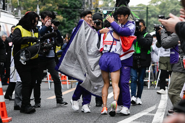 ゴールした10区の庭瀬俊輝（3年）を柔らかな表情で出迎えた鈴木と副将の金子（左）　©Nanae Suzuki