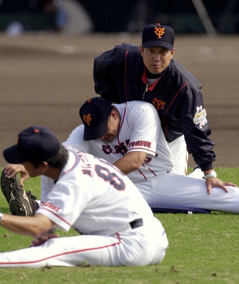 長嶋茂雄から監督の座を受け継いだ秋季キャンプ、アルモンテ投手のストレッチを手伝う原辰徳　©︎JIJI PRESS